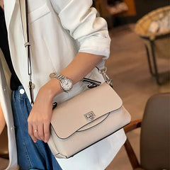 Person holding a beige handbag with a blurred indoor background