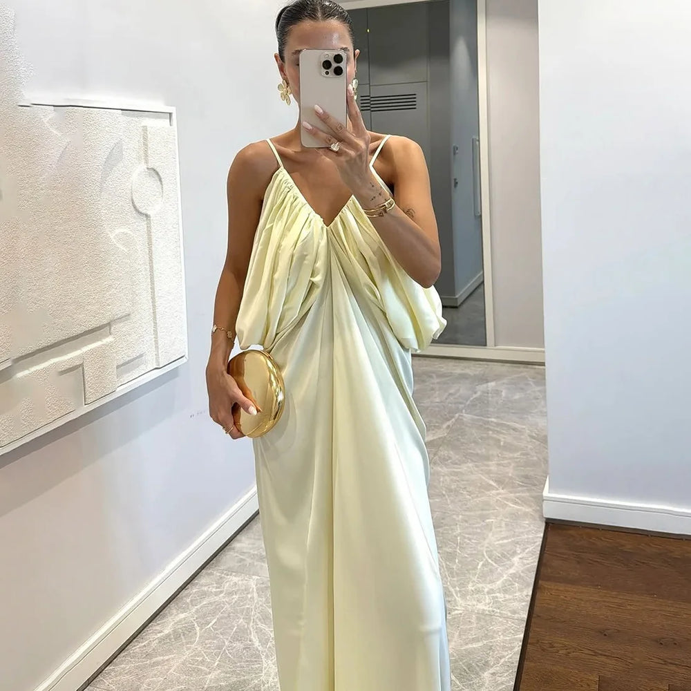 Woman in a light green dress taking a mirror selfie in an indoor setting.