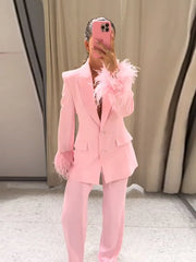 Person wearing a pink suit with feathered accents in front of a neutral background
