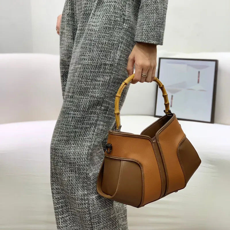 Close-up of a woman holding a bamboo handle colorblock leather handbag