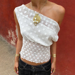 Woman wearing a white polka dot top with a red wall background