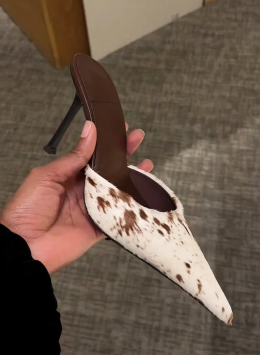 Cow print stiletto heel being held