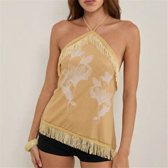 Woman wearing a mustard yellow halter top with floral design and fringe details.