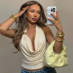 Woman holding a phone and a yellow clutch against a plain background