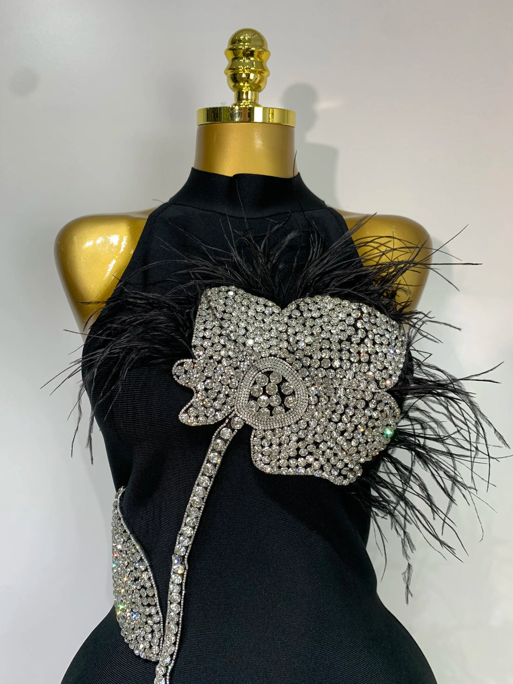 Close-up of diamond and feather floral embellishment on turtleneck sleeveless midi dress.