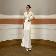 Woman in a white dress standing in an elegant room with decorative walls.