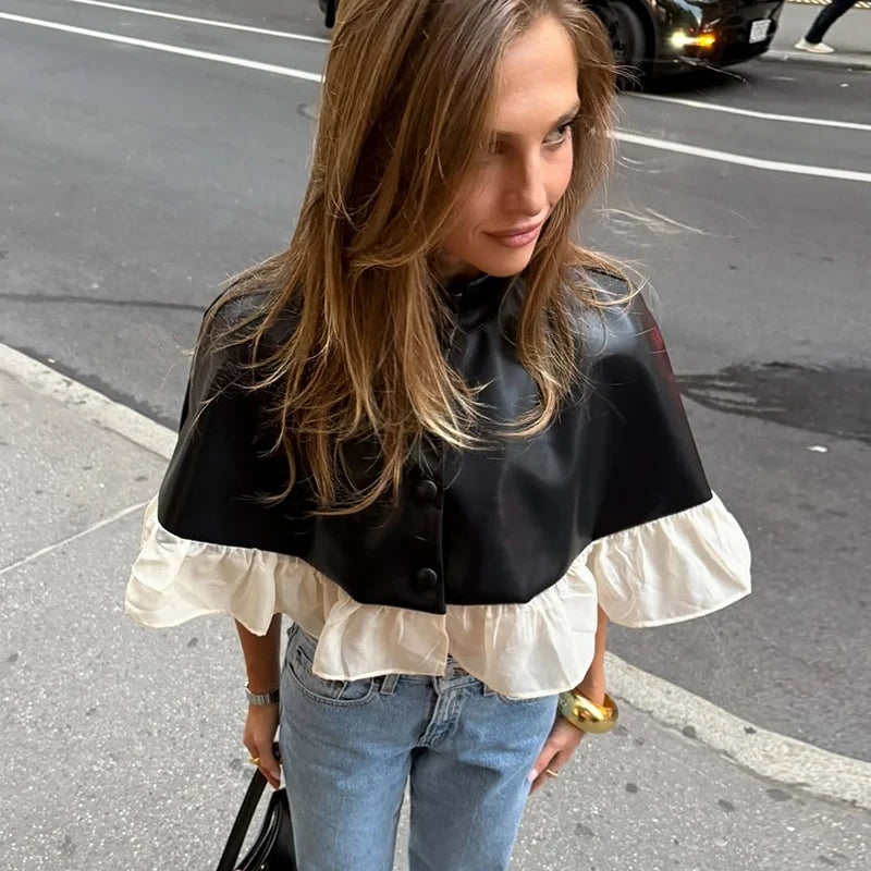 Woman wearing a black and white layered blouse with blue jeans on a street.