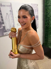Woman in a gold dress holding a golden award in front of a blurred background