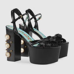 Black leather platform sandals with a chunky block heel and pearl detail.