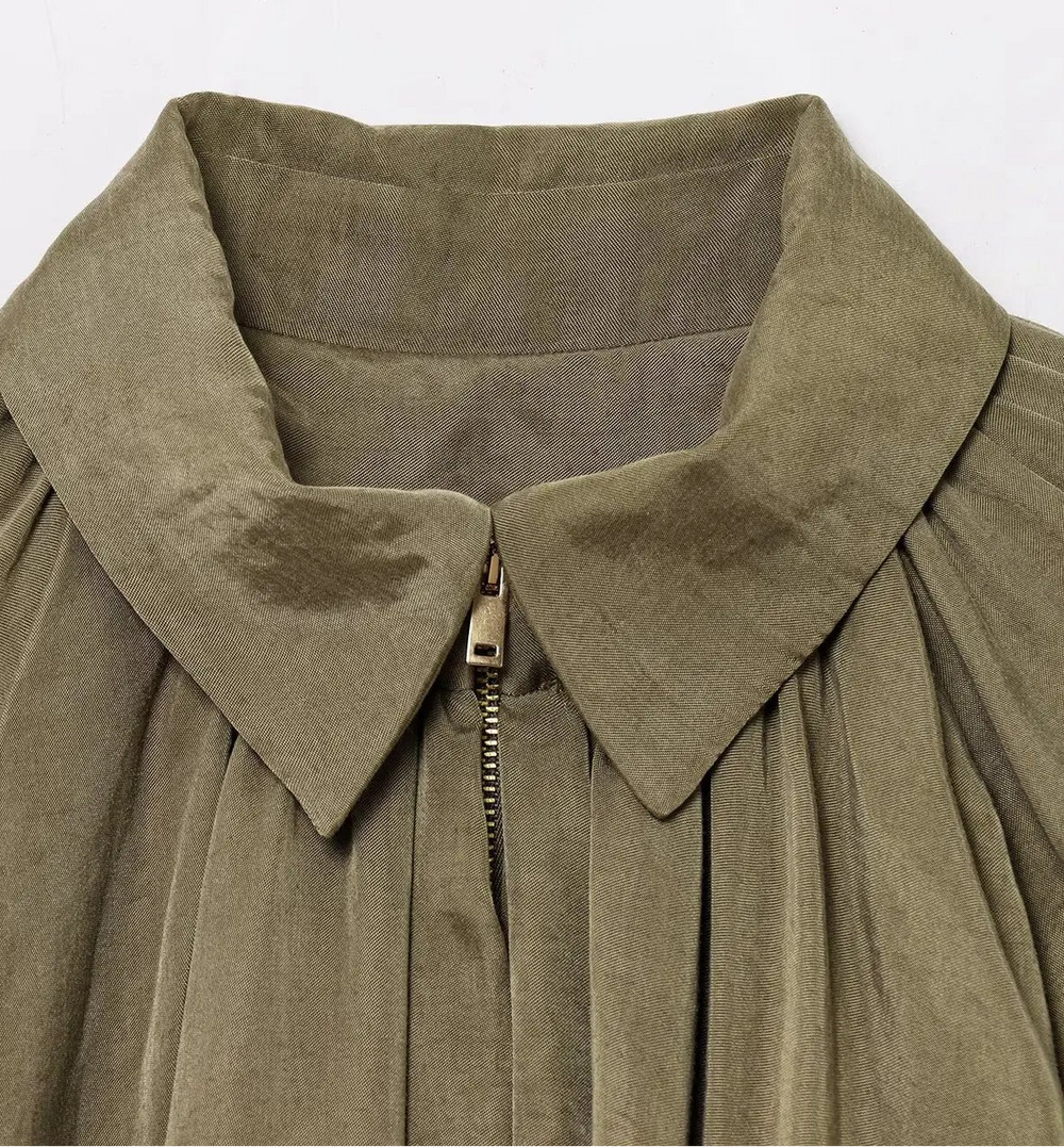 Close-up of a green garment with a collar and zipper on a white background