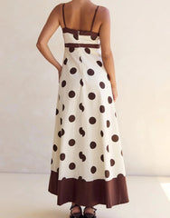 Woman wearing a polka dot dress with brown and white pattern on a plain background