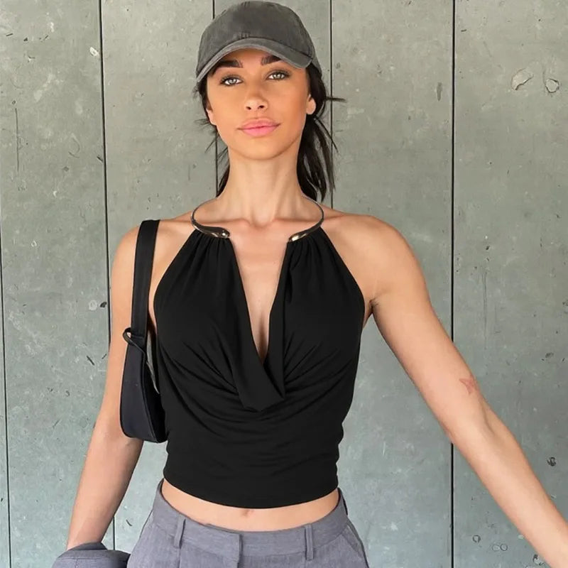 Woman wearing a black halter top and gray cap against a gray wall