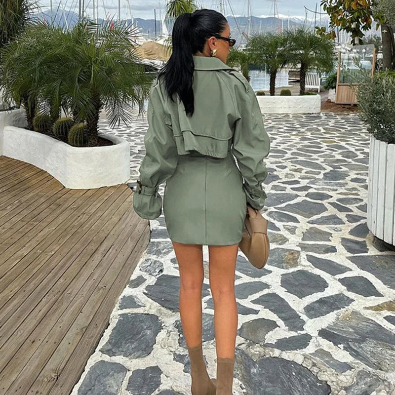 Woman in a green outfit walking on a stone path with plants and wooden deck in the background