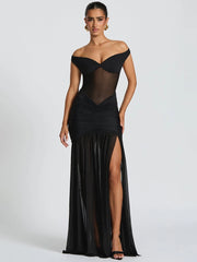 Woman wearing a black off-shoulder evening gown with a high slit on a white background