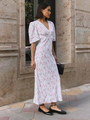 Woman wearing ankle-length white floral summer dress with V-neck and short sleeves.