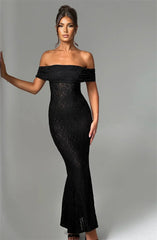 Woman wearing a black off-shoulder lace dress against a gray background