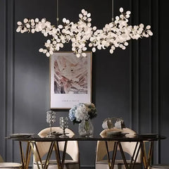 Modern chandelier hanging above a dining table with chairs in a darkly decorated room.