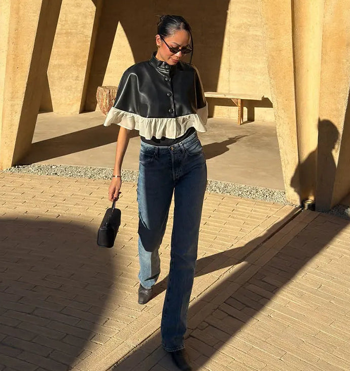 Woman walking outdoors in a sunlit area with architectural columns.