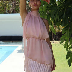 Woman wearing a pink sleeveless top by a poolside with greenery in the background