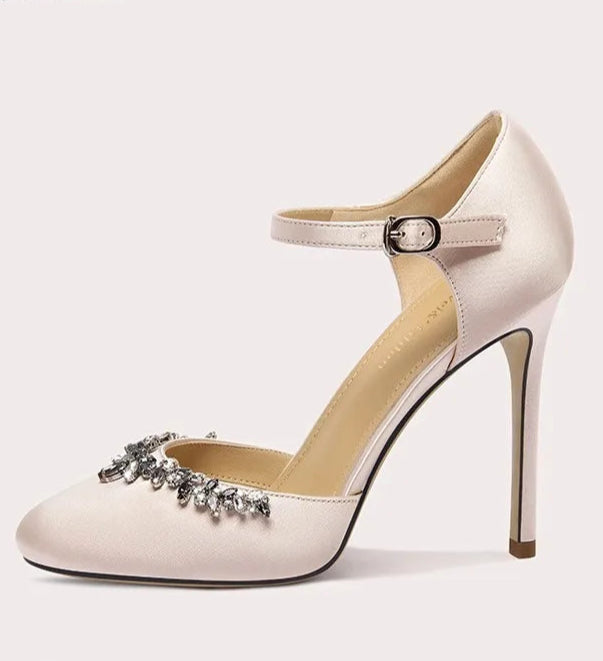 White high-heeled shoe with decorative strap on a light gray background