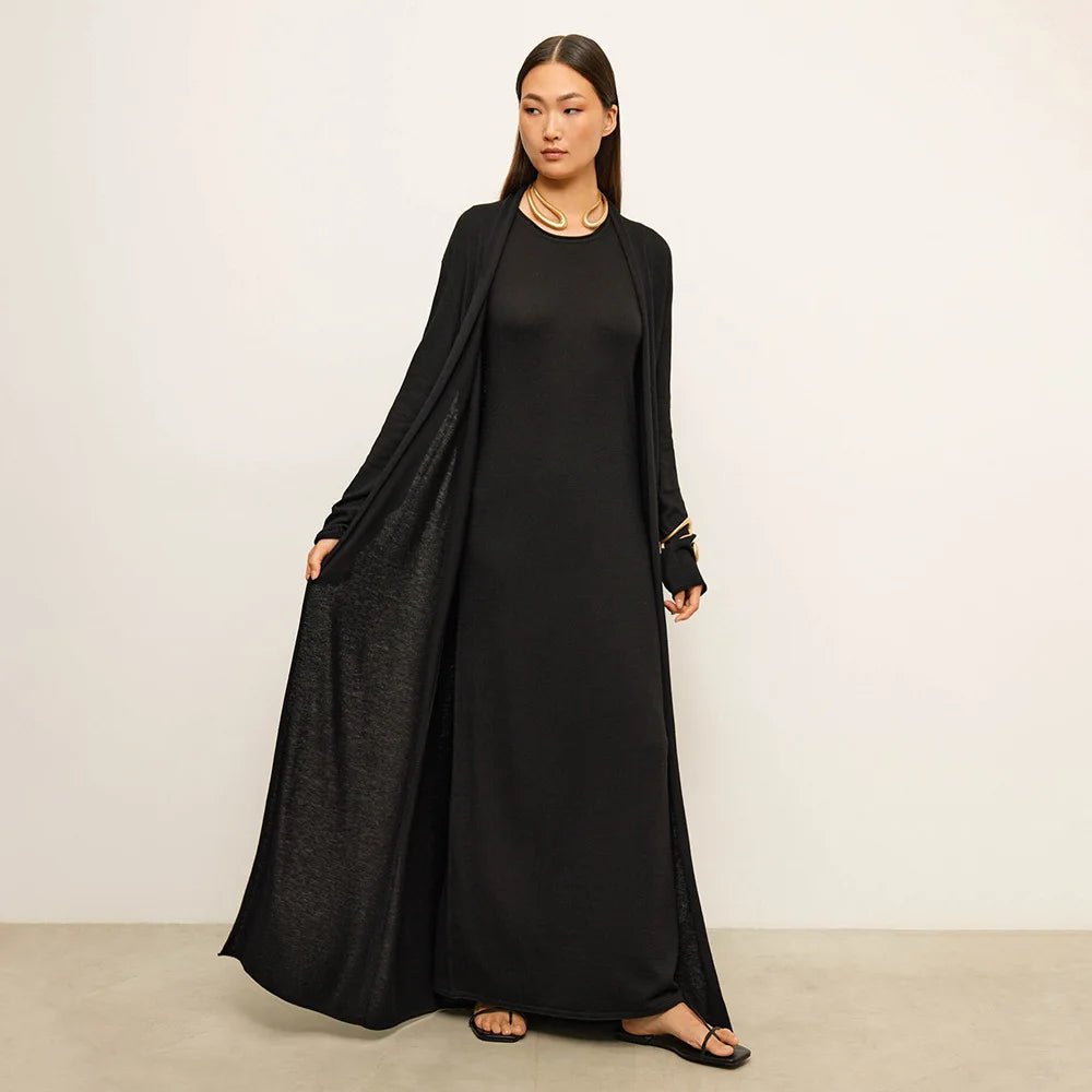 Woman wearing a black long-sleeve dress against a plain background