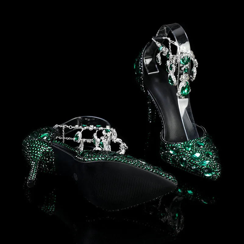 Black high-heeled shoes with green gemstones on a black background