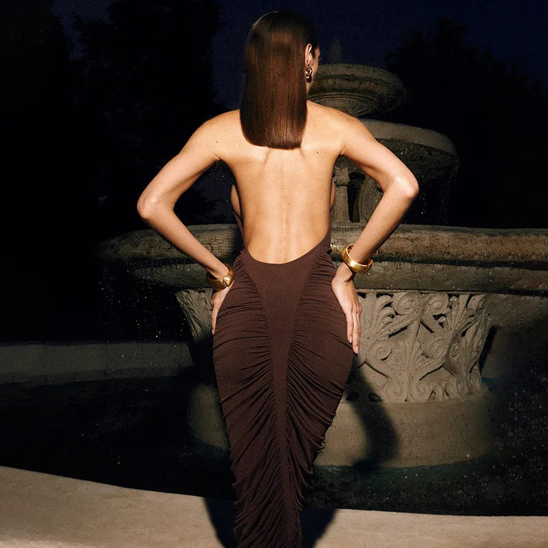 Woman in a brown dress with a low back, standing on stone steps at night.