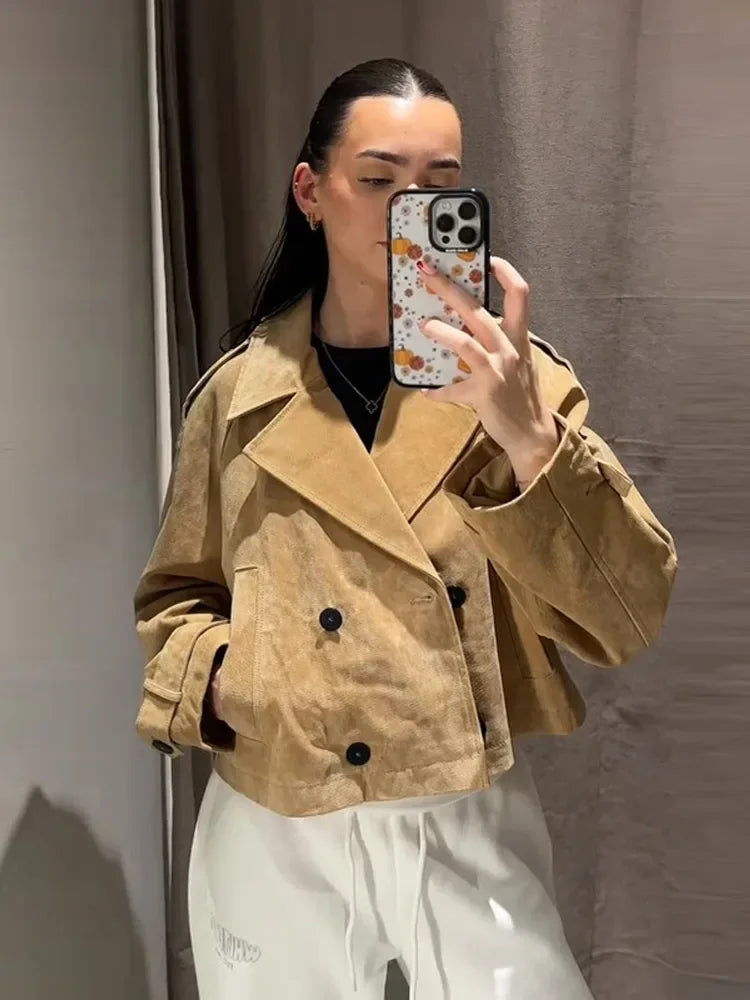 Person wearing a beige trench coat taking a mirror selfie.