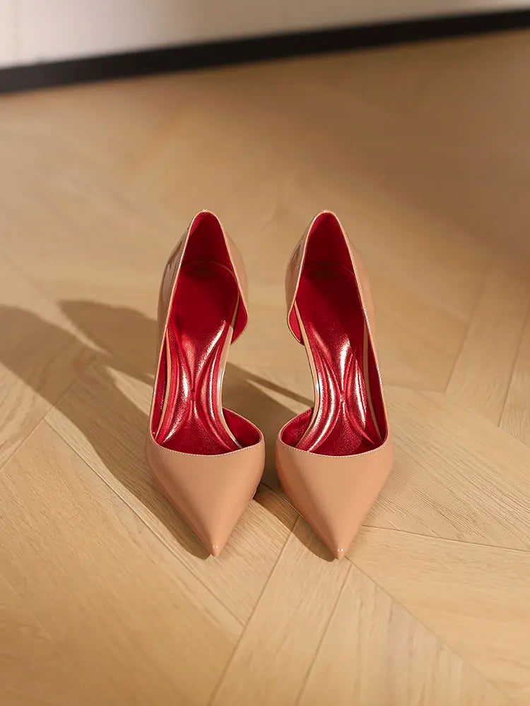 Pair of high-heeled shoes with red soles on a wooden floor