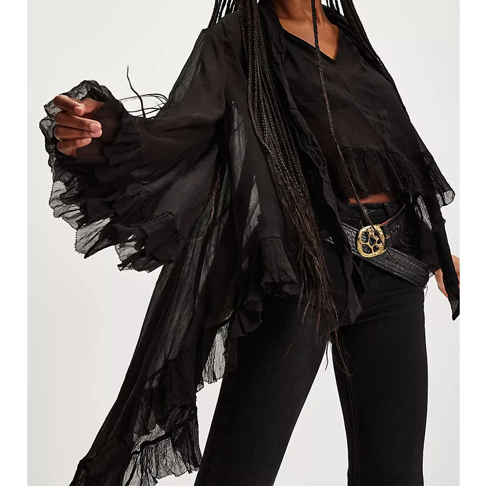 Person wearing a black outfit with ruffled sleeves and a belt on a white background