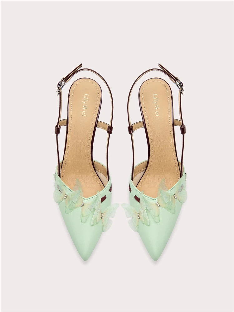 Pair of light green high-heeled shoes with decorative elements on a white background