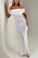 Woman wearing a white off-shoulder lace dress against a plain background