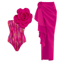 Pink abstract print one-shoulder swimsuit with a large pink floral applique and a ruffled pink sarong.
