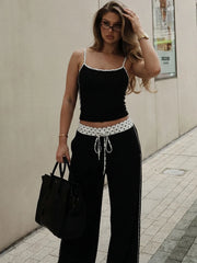 Close-up of black camisole top and wide-leg pants set with polka dot trim