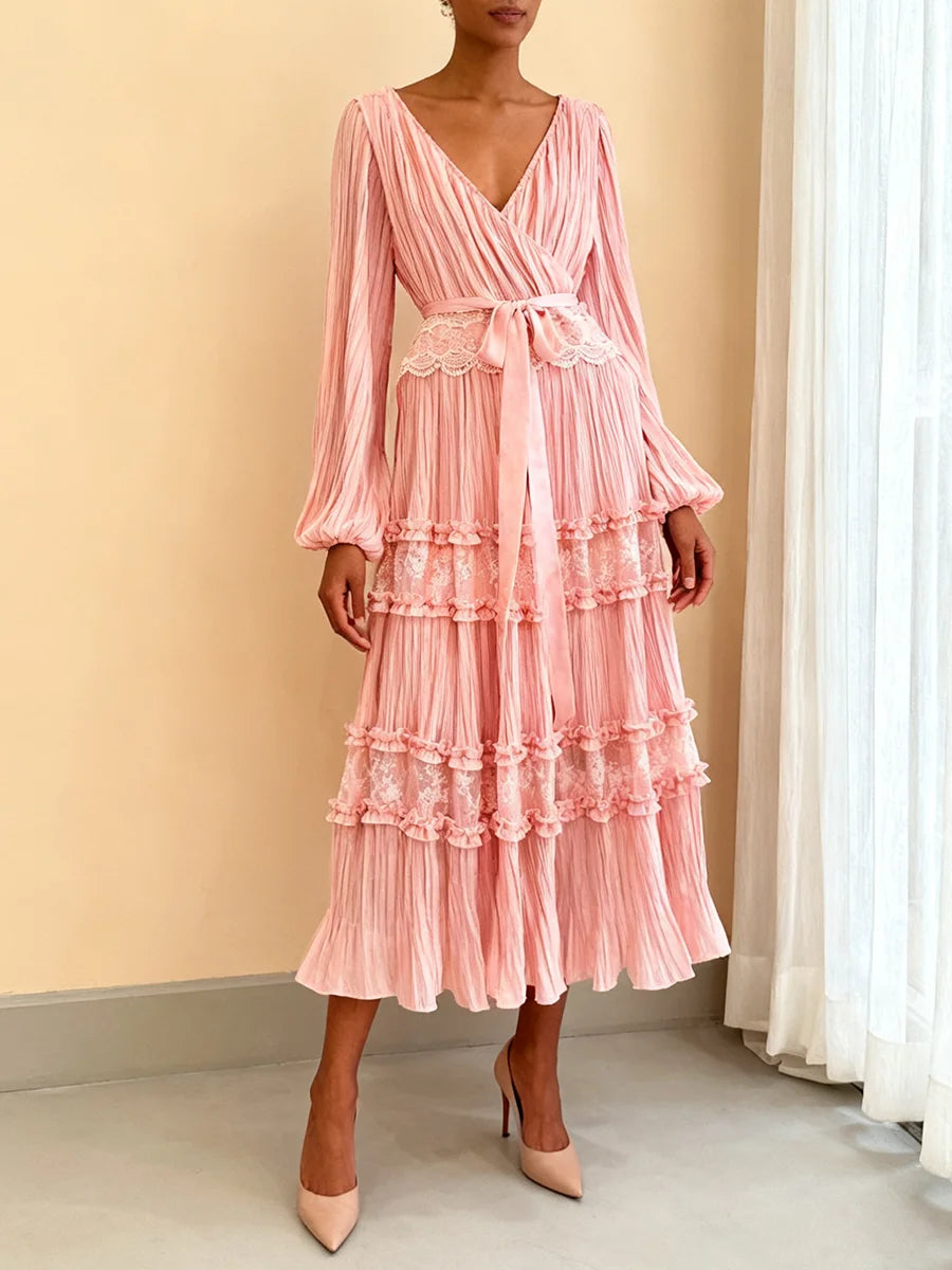 Woman wearing a pink ruffled dress against a beige wall.