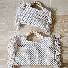Two woven bags with tassels on a textured surface