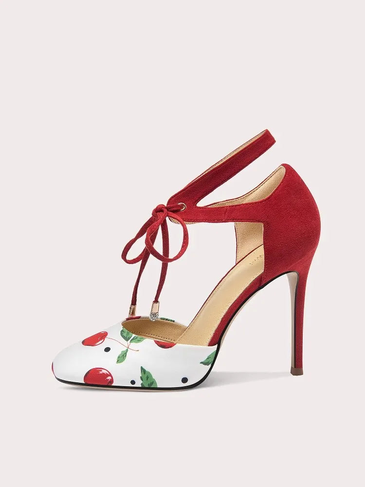 Red high-heeled shoe with white sole featuring cherry design on a light gray background