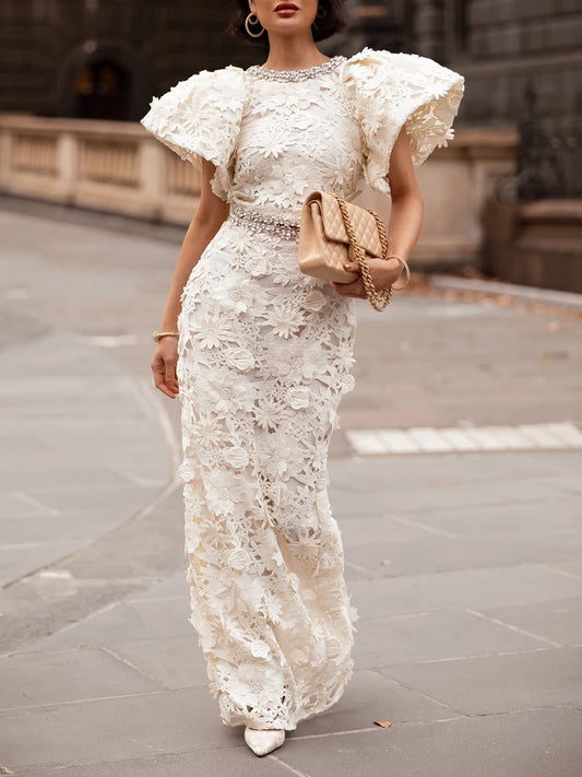 Close-up of the crystal embellishment on the neckline of a white lace gown.