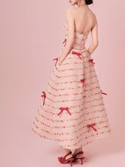 Woman wearing a strapless dress with red bows on a pink background