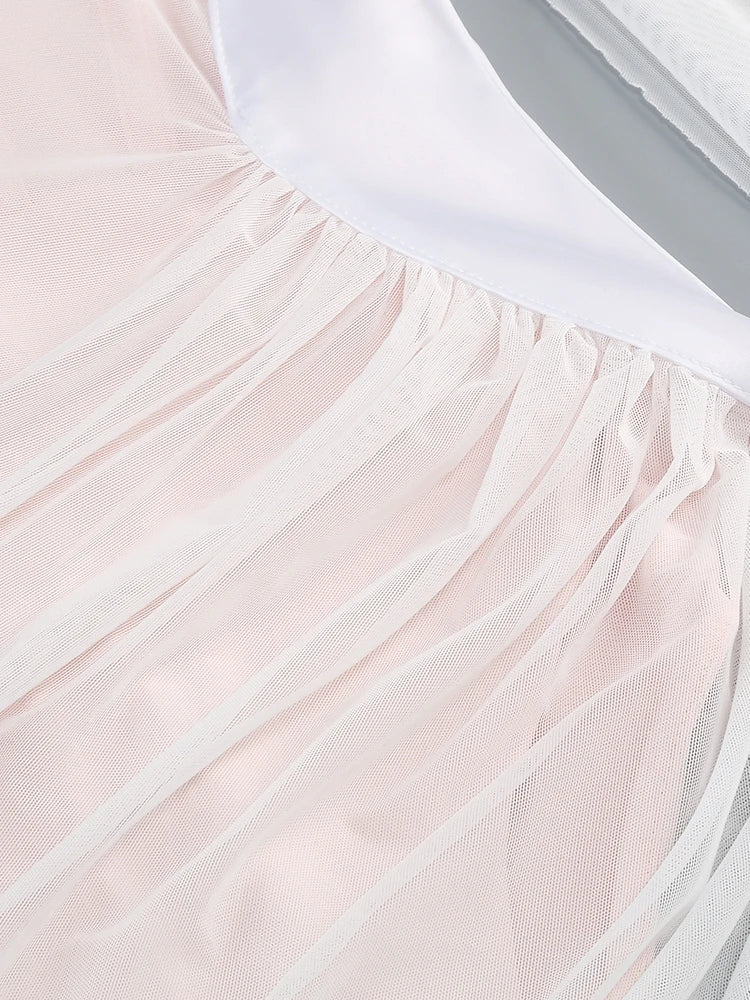 Close-up of a light pink tulle skirt with a white top underneath.