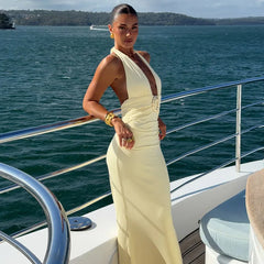Woman in a white dress standing on a boat with water and sky in the background