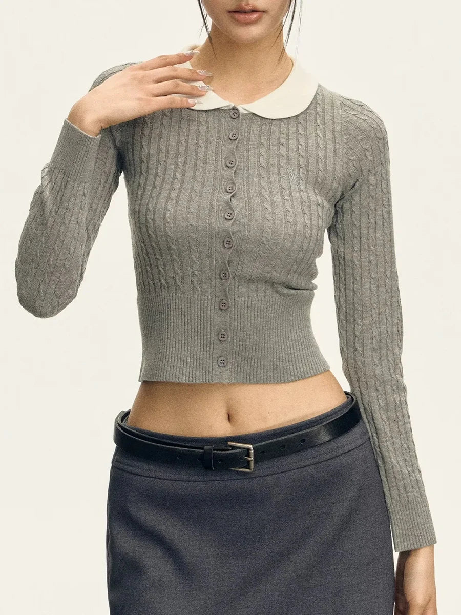 Woman wearing a gray ribbed sweater with a white collar and black skirt on a plain background