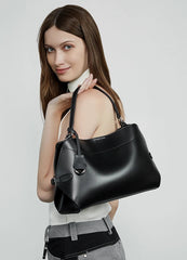 Woman holding a black handbag against a light gray background