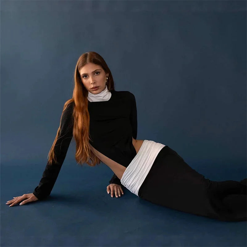 Woman in a black outfit with white accents on a blue background