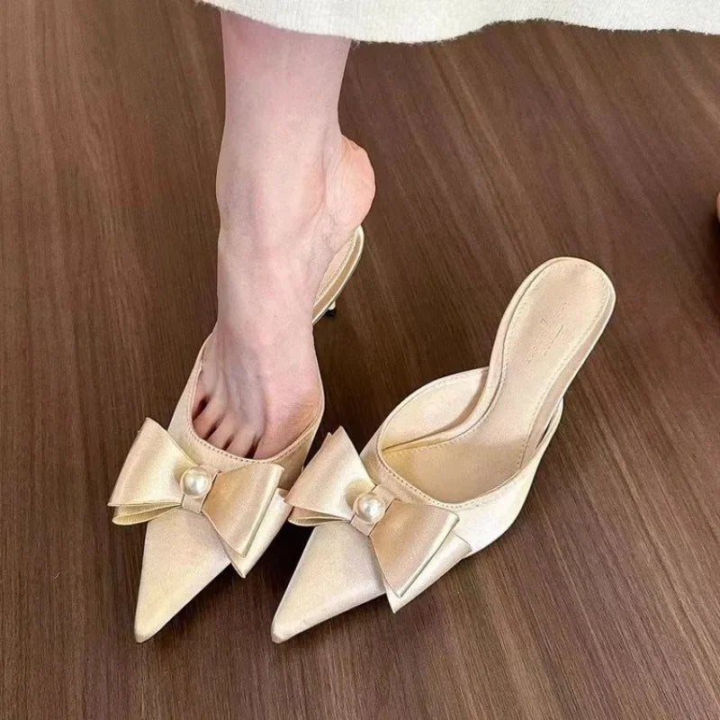  A woman wearing elegant beige bowknot kitten heels with pointed toes, perfect for formal events. 1