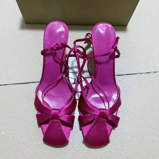Top view of pink satin stiletto heels with bow and ankle straps