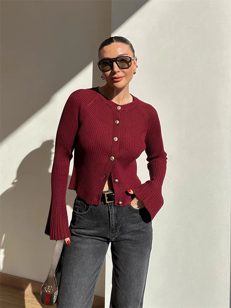 Person wearing a red cardigan and sunglasses against a light-colored wall