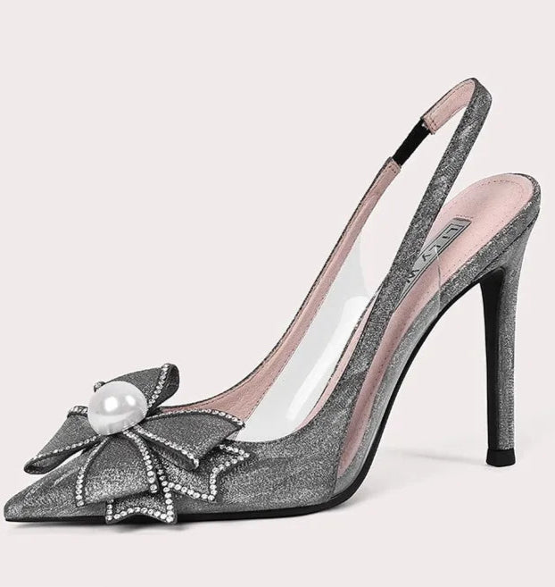 High-heeled shoe with decorative bow and pearl on a light gray background