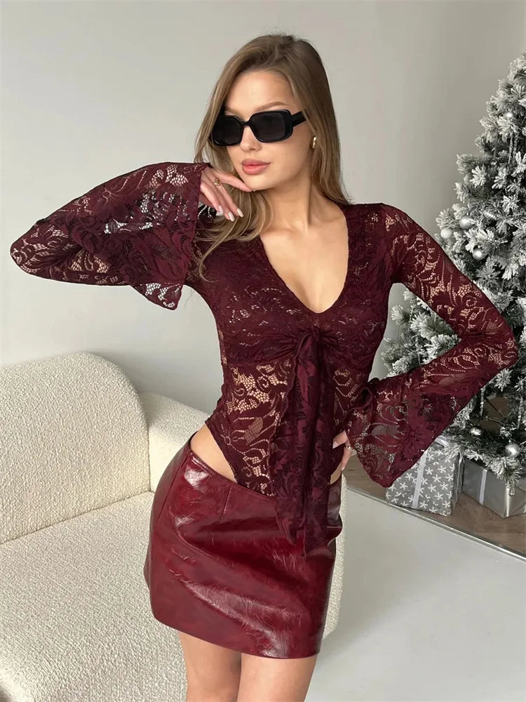 Woman wearing a burgundy lace top and leather skirt in a room with a Christmas tree.