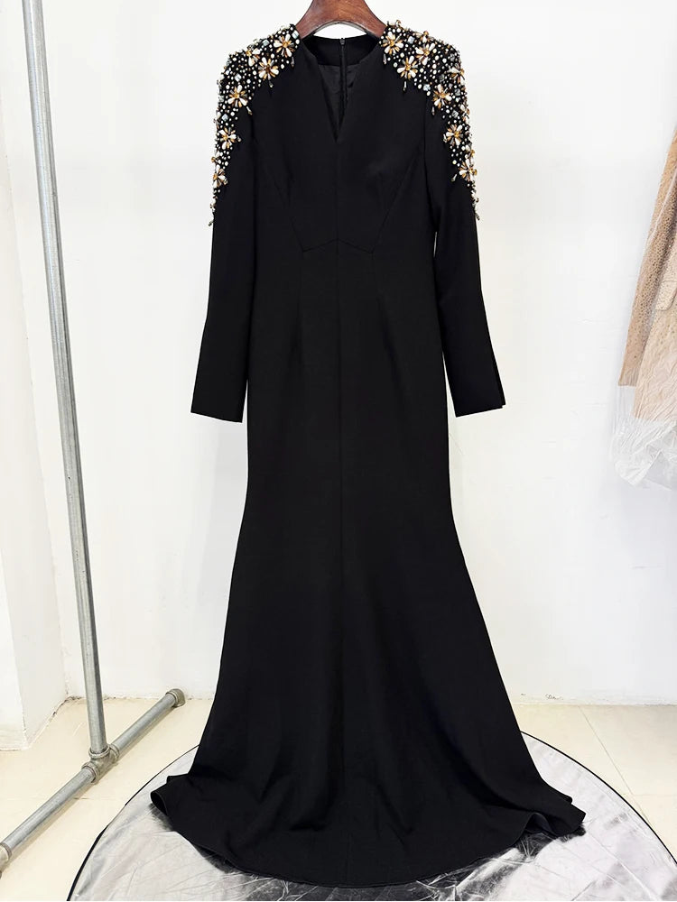 Black dress with gold embellishments on shoulders against a white background